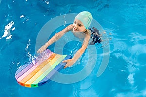 Swimming class. Close up of kids practicing flutter kick with kick board in swimming pool