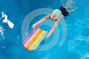 Swimming class. Close up of kids practicing flutter kick with kick board in swimming pool