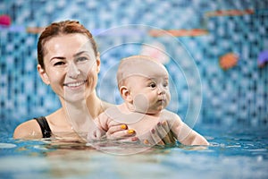 Swimming classes for little ones, infant with mother in swimming pool during training