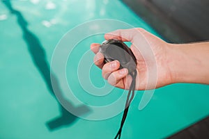 Swimming coach holding stopwatch poolside