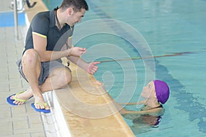 Swimming coach holding stopwatch poolside at leisure center