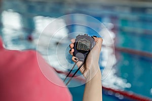 Swimming coach holding stopwatch poolside at the leisure center.