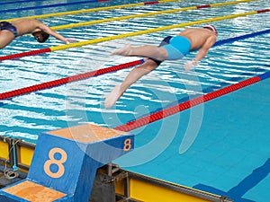 swimming competition, two swimmers were jumping from colorful platform starting point into swimming pool