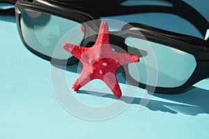 Swimming goggles and a starfish on a blue background. marine theme, preparation for summer