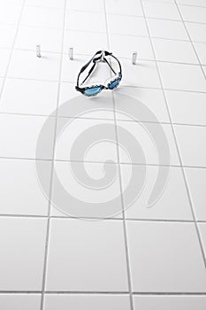 Swimming goggles on white tile wall