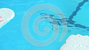 Swimming instructor teaches children to swim in the pool using a swimming board