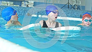 Swimming instructor teaches children to swim in the pool using a swimming board