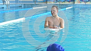 Swimming instructor teaches children to swim in the pool using a swimming board