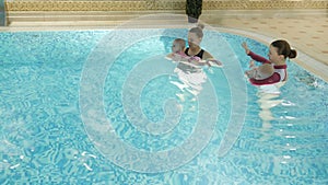 Swimming lesson. Mothers teaching to swim newborn baby at swimming pool