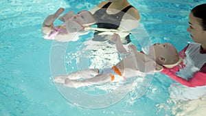 Swimming lesson. Mothers teaching to swim newborn baby at swimming pool