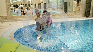 Swimming lesson. Mothers teaching to swim newborn baby at swimming pool