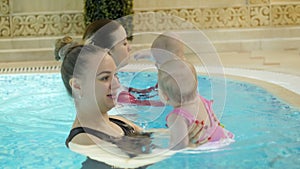 Swimming lesson. Mothers teaching to swim newborn baby at swimming pool