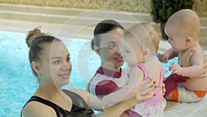 Swimming lesson. Mothers teaching to swim newborn baby at swimming pool