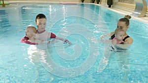 Swimming lesson. Mothers teaching to swim newborn baby at swimming pool