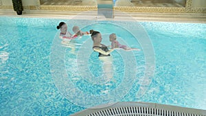 Swimming lesson. Mothers teaching to swim newborn baby at swimming pool