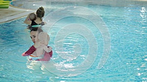 Swimming lesson. Mothers teaching to swim newborn baby at swimming pool