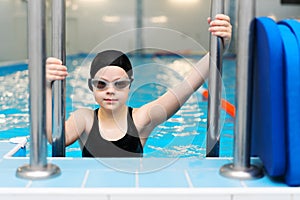 Swimming lessons for children in the pool - beautiful fair-skinned girl swims in the water