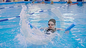 Swimming lessons for children in the pool - beautiful fair-skinned girl swims in the water