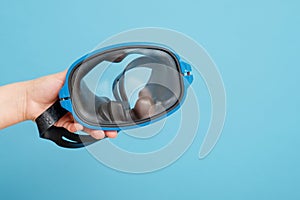 Swimming mask in a female hand on background