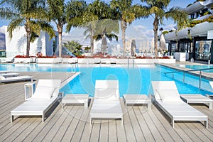 Swimming pool area with white sun beds at the modern resort.