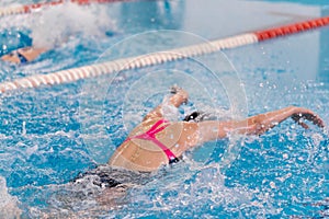 Swimming pool athlete training indoors for professional competition. Female swimmer performing the butterfly stroke at