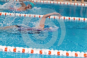 Swimming pool athlete training indoors for professional competition. Teenager swimmer doing free style