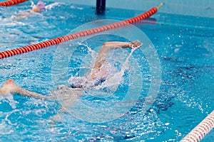 Swimming pool athlete training indoors for professional competition. Teenager swimmer doing free style