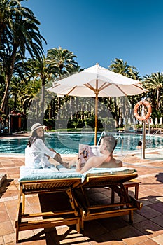 Swimming pool with bed chairs luxury resort, couple men and woman relaxing in beach chair by the pool