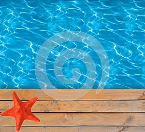 Swimming pool with blue clear water and wooden deck with star-fish