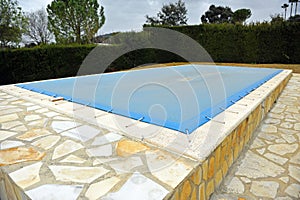 Swimming pool with a blue tarp for protection in winter