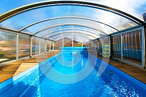 Swimming pool with blue water and transparent plastic tent. Modern pool design with collapsible wall and ceiling photo
