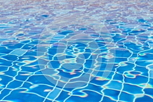 Swimming pool blur water with wavy reflective blue tile underwater in cool blue color for summer background