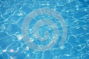 Swimming pool bottom caustics ripple and flow with waves background. Summer background. Texture of water surface