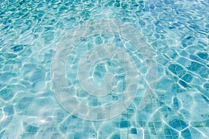 Swimming pool bottom caustics ripple and flow with waves background. Summer background. Texture of water surface.