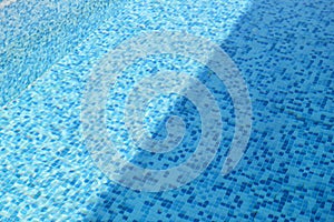Swimming pool bottom caustics ripple and flow with waves background. Surface of blue swimming pool, background of water.