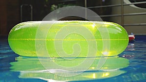 Swimming pool with a brightly yellow inflatable ring in slow motion and shining reflecting sun on the water. 1920x1080