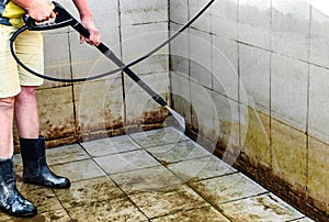 Swimming pool cleaning. A service man is cleaning the pool ground with a high-pressure washer.