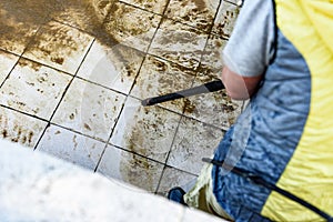 Swimming pool cleaning. A service man is cleaning the pool ground with a high-pressure washer.