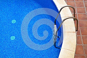 Swimming pool with a clear blue water and steel ladder in the resort.