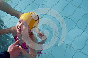 Swimming pool coach teaches a little girl to swim and dive under water