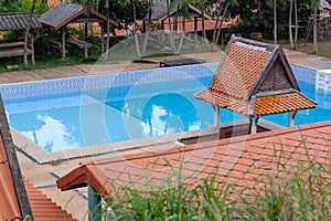 Swimming pool with covered porch and leaves on bottom, shot through tiled roof. Horizontal