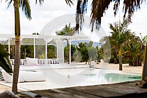 Swimming pool and deck with outdoor furniture and palm trees at tropical beach resort, copy space