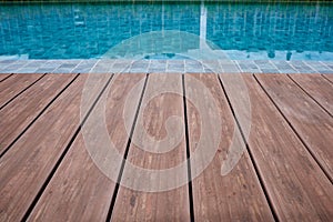 Swimming pool deck wood floor and blue water background.