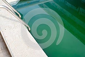 Swimming pool with dirty green water close-up