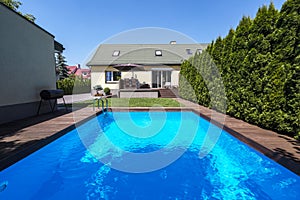 Swimming pool in the garden of house with trees during summer. R