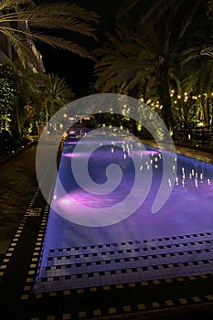 Swimming pool in the hotel with beautiful purple lighting at night