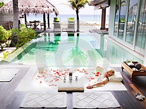 Swimming pool, hotel and relax with woman in bathtub for skincare, aromatherapy and tropical Bali vacation in villa