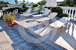 Swimming pool of luxury holiday villa, amazing nature. Relax near swimming pool with handrail, deck chairs, sun loungers.