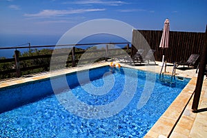 Swimming pool of luxury holiday villa, amazing nature view landscape sea. Relax near swimming pool with handrail, deck chairs.