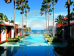 Swimming pool in a luxury hotel resort overlooking the beach and sea on sky, relaxation holiday vacation.